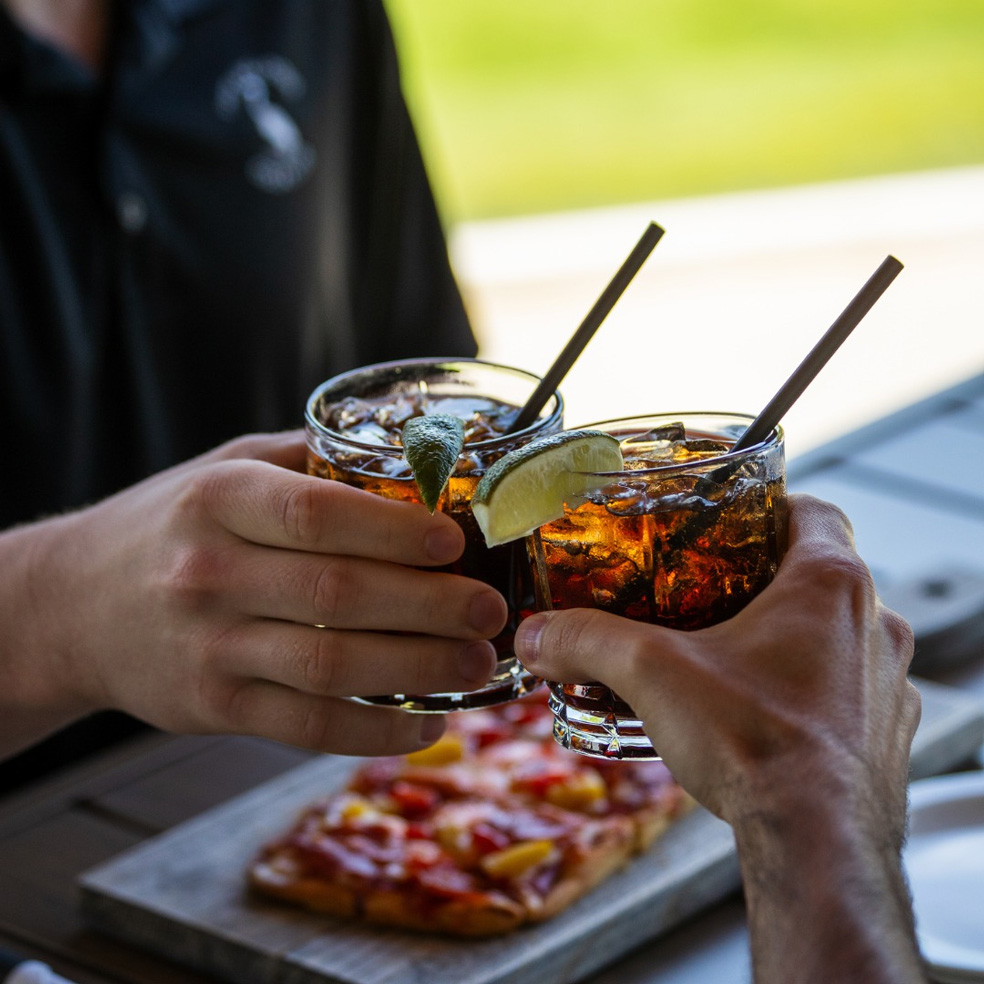 Two-hands-clinking-glasses-of-dark-drinks-with-lime-wedges-Pitt-Meadows-Golf-Club